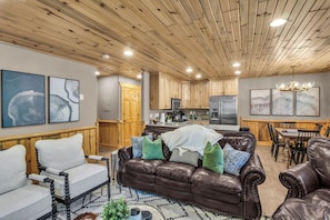 A spacious living room with a brown leather sofa, a white armchair, and a patterned rug. - Timber Wolf 11B | Creekside | Canyons Village | Hot Tubs | Fireplace | Free Bus (Park City)