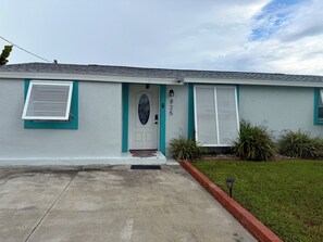 A single-story house with a front door, two windows with shutters, a small porch, and a number '825' on the wall. - 3 BR waterfront house 25 minutes from TAMPA!! Feat. Pool Kayaks, FIshing & Dock! (Ruskin)