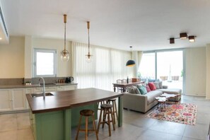 A modern kitchen with a central island, bar stools, and pendant lighting. - beafront Pethouse 3 bdrms w Jacuzzi (Haifa)