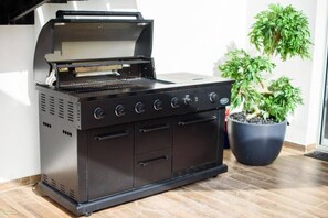 A black outdoor grill with a hood, four control knobs, and a built-in oven. - beafront Pethouse 3 bdrms w Jacuzzi (Haifa)