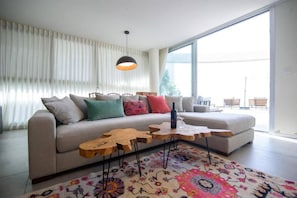 A modern living room with a sofa, decorative pillows, a wooden coffee table, and a colorful rug. - beafront Pethouse 3 bdrms w Jacuzzi (Haifa)