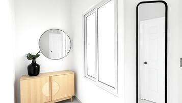A hallway with a wooden cabinet, a round mirror, and a door.