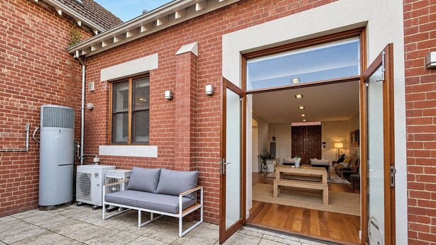 A residential property with a brick exterior, a sliding glass door leading to an interior with a sofa and a dining area. - Wake up and walk to the Sunday market (Alphington)