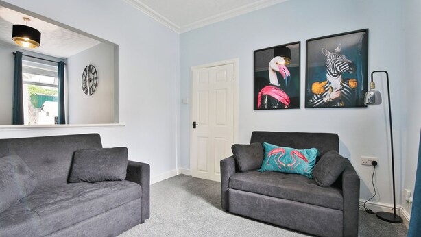A living room with two grey sofas, a white door, and two abstract paintings on the wall. - 2BR Designer Home near Swansea City Centre (Swansea)
