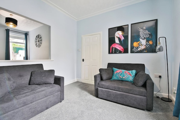 A living room with two grey sofas, a white door, and two abstract paintings on the wall. - 2BR Designer Home near Swansea City Centre (Swansea)
