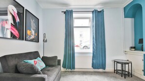 A living room with a grey sofa, teal curtains, a small round table, and a framed zebra picture. - 2BR Designer Home near Swansea City Centre (Swansea)