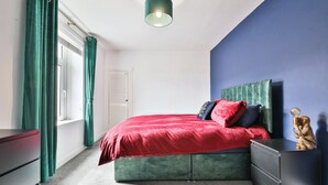 A bedroom with a bed, a dresser, a nightstand, and a lamp. - 2BR Designer Home near Swansea City Centre (Swansea)