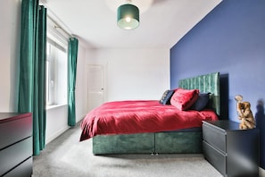 A bedroom with a bed, a dresser, a nightstand, and a lamp. - 2BR Designer Home near Swansea City Centre (Swansea)