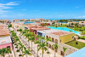 A resort with multiple buildings, a central pool, and palm trees. - Junior Suite at Fishing Lodge Cap Cana (Punta Cana)