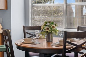 A round dining table with a vase of flowers, plates, and glasses. - Cozy at the Cove - Pool Access (Branson)
