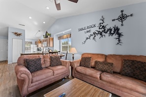 A living room with a brown leather sofa set, a coffee table, and a wall art piece depicting a map of Table Rock Lake. - Cozy at the Cove - Pool Access (Branson)