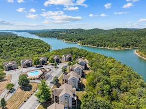A residential area with multiple two-story houses, a swimming pool, and a river. - Cozy at the Cove - Pool Access (Branson)