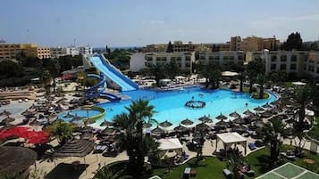 A resort with a large central pool, multiple water slides, and a surrounding lounge area with umbrellas.