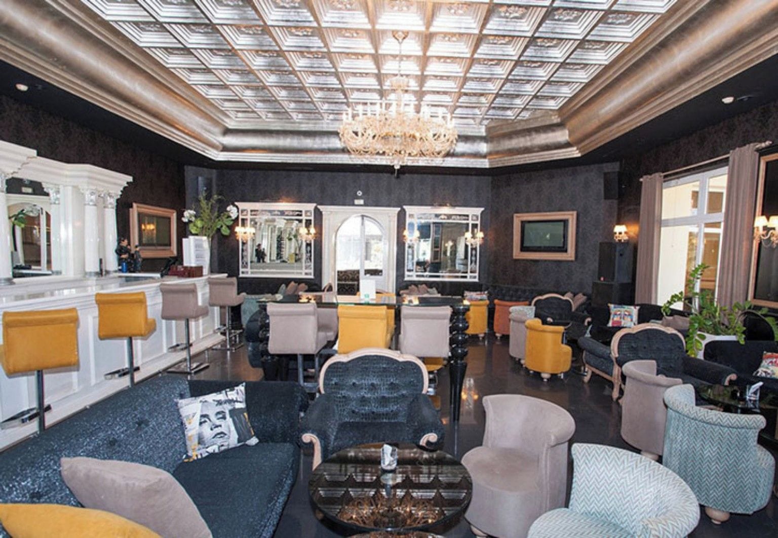 Un amplio salón con techo alto, candelabros y diversas opciones de asiento, incluyendo sofás y sillones.