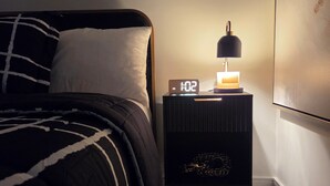 A bedroom with a bed, a bedside table with a clock, and a wall-mounted artwork. - Stylish Studio Suite w/ Private Entrance | Parking (Brampton)