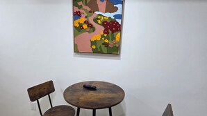 A dining area with a round wooden table and four chairs, a painting on the wall, and a power outlet on the wall. - Stylish Studio Suite w/ Private Entrance | Parking (Brampton)