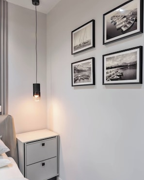 Ein Schlafzimmer mit einem Nachttisch, einer Lampe und vier gerahmten Fotos an der Wand.