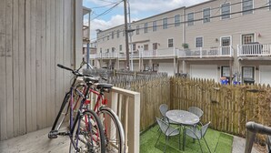 Ein Wohngebäude mit Balkon, einem Fahrrad und einer kleinen Terrasse mit Tisch und Stühlen.