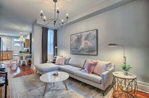 A modern living room with a sectional sofa, a round coffee table, and a chandelier.