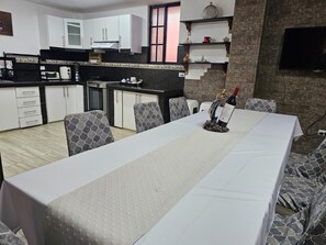 Un comedor con una mesa larga, sillas y una botella de vino sobre un soporte.