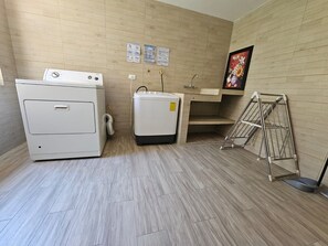 Una sala de lavandería con lavadora, secadora y tendedero.