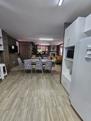 Una cuina moderna amb zona de menjador, que destaca per un forn integrat, armaris blancs i una taula de dinar amb cadires estampades.