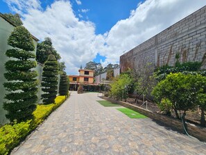 Un patio con un sendero adoquinado, un edificio con tejado de baldosas y un muro de ladrillo.
