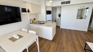 Cozinha moderna com armários brancos, uma ilha central e um espaço de jantar com mesa e cadeiras brancas.