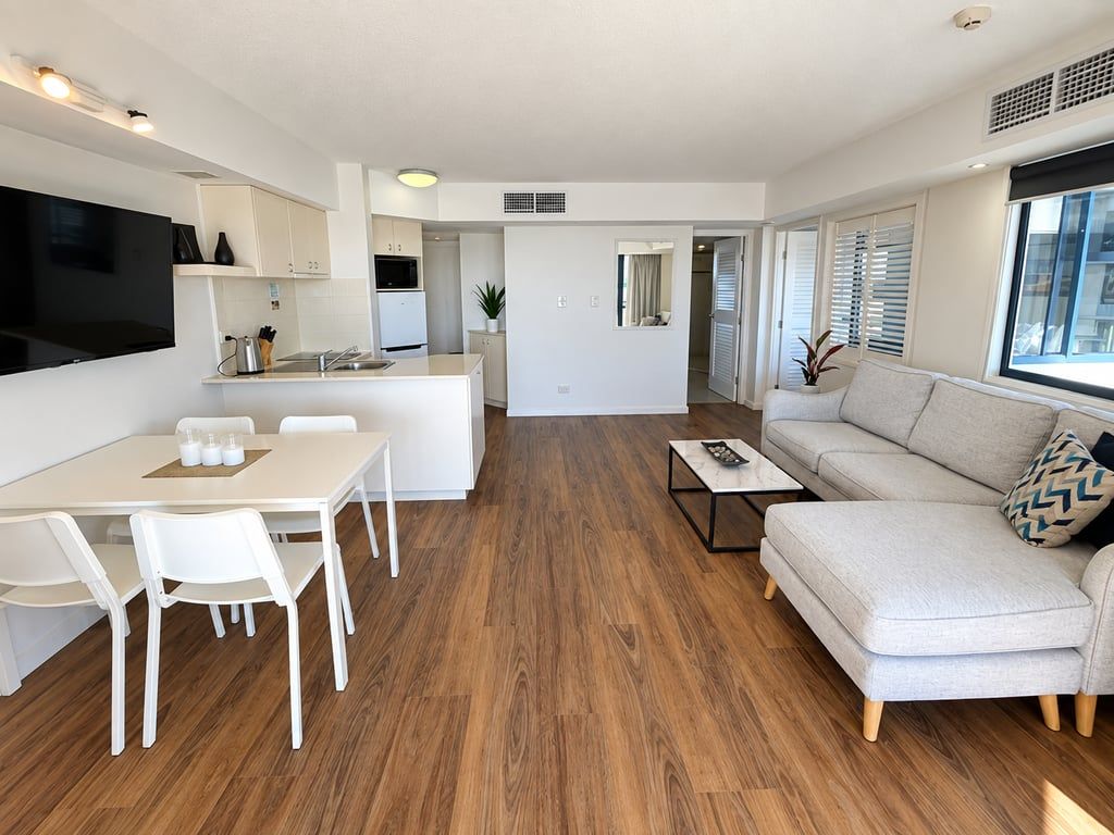 Uma sala de estar moderna com sofá, mesa de centro e área de jantar com cadeiras e mesa.