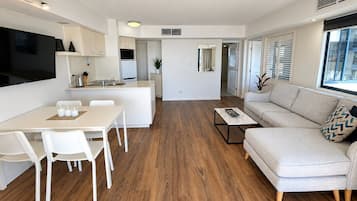 Uma sala de estar moderna com sofá, mesa de centro e área de jantar com cadeiras e mesa.