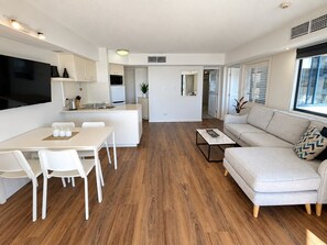 Uma sala de estar moderna com sofá, mesa de centro e área de jantar com cadeiras e mesa.
