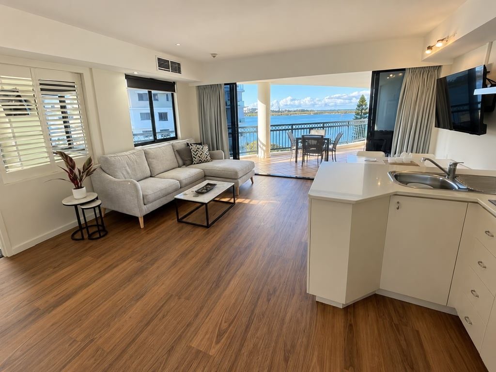 Sala de estar moderna com sofá, mesa de centro e vista para uma varanda com área de refeições.
