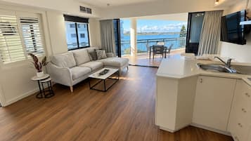 Sala de estar moderna com sofá, mesa de centro e vista para uma varanda com área de refeições.