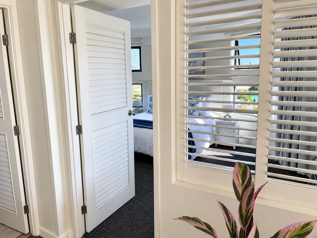 Une chambre d’hôtel avec un lit, un bureau et une fenêtre équipée de stores.