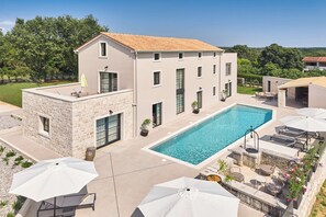 A modern house with a swimming pool, stone exterior, and outdoor seating. - Luxury Villa Madora for up to 12 guests by Istrabook (Poreč)