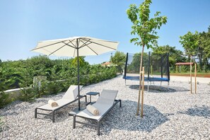 A sunlit outdoor area with two lounge chairs, a large umbrella, and a trampoline. - Luxury Villa Madora for up to 12 guests by Istrabook (Poreč)