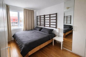 A bedroom with a bed, bedside table, and a mirror. - Superbe Apt @ MTL | Proche Métro | Parking & Wi-Fi (Longueuil)