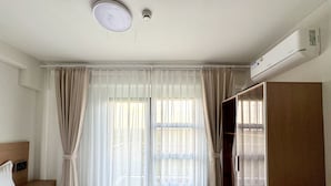 Une chambre d’hôtel avec un lit, une armoire, un bureau et une fenêtre avec des rideaux.