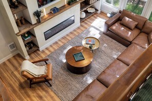 Un salon moderne avec un canapé en cuir marron, une table basse ronde et un tapis à motifs.