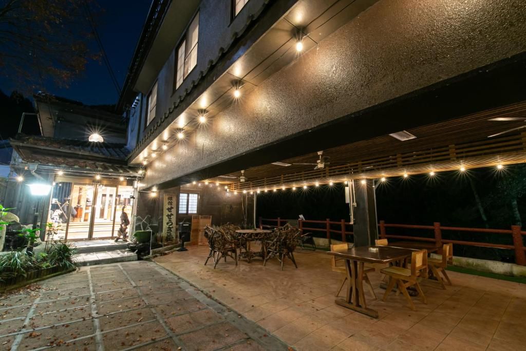 An outdoor patio area with a dining table and chairs, a covered seating area, and a building entrance.