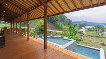 Une terrasse en bois avec une piscine et une vue sur un paysage luxuriant.
