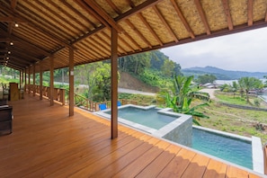 A wooden deck with a pool and a view of a lush landscape.