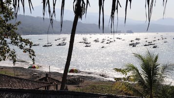 Une plage avec des bateaux, des parasols et une structure à toit de chaume.