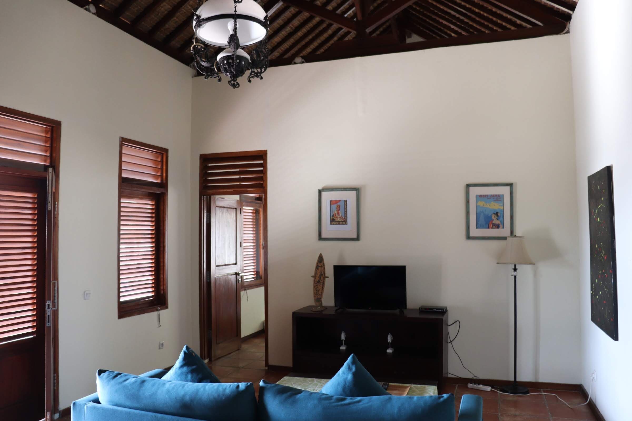 A room with a sofa, television, and artwork on the wall.