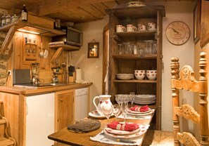 Una cocina rústica con armarios de madera, una mesa de comedor para dos personas y un reloj en la pared.