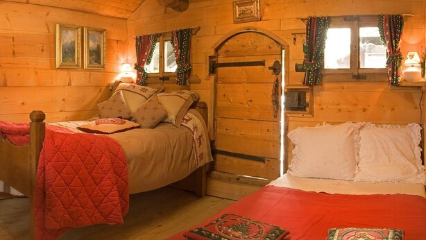 A cozy cabin room with two beds, wooden walls, and a door with a window. - CANTATES CHALET with Private Jacuzzi on VRBO (Chamonix Mont-Blanc)