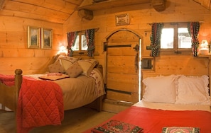 A cozy cabin room with two beds, wooden walls, and a door with a window.