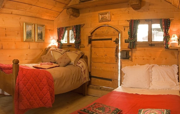 Acogedora habitación tipo cabaña con dos camas, paredes de madera y una puerta con ventana.