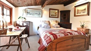 Una stanza accogliente con un letto di legno, una scrivania con una sedia e una finestra.