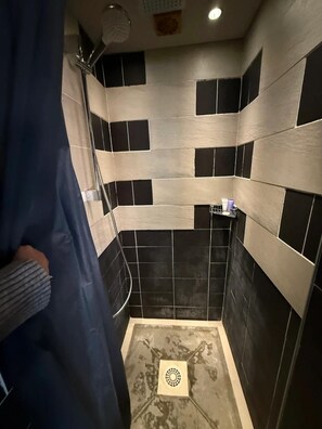 A bathroom with black and white tiles, a shower, and a toilet.